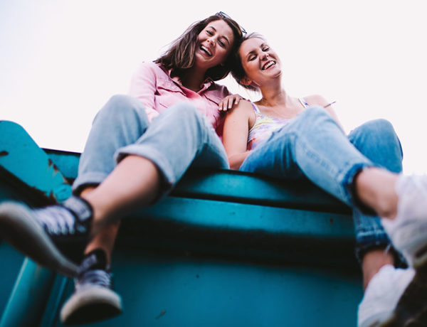 Two friends hanging out and smiling while sitting together outside.