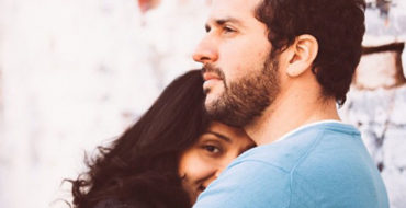 A woman who is wondering what to do when he says he loves you, hugging her boyfriend and smiling.