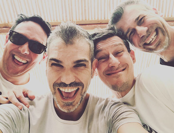 A group of guys who learned how to make friends in college laughing and taking a selfie together.