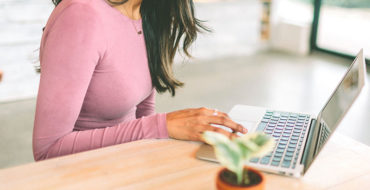 A woman online dating while sitting at her computer in her kitche.