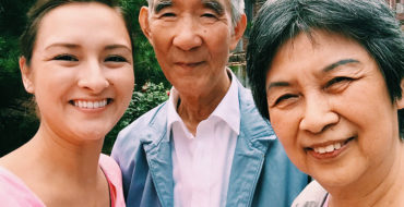 A woman standing with her parents, about to meet her significant other.