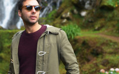 A guy standing outside looking cool in his sunglasses, who shows some of the signs of a player.