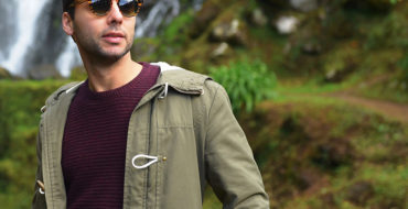 A guy standing outside looking cool in his sunglasses, who shows some of the signs of a player.