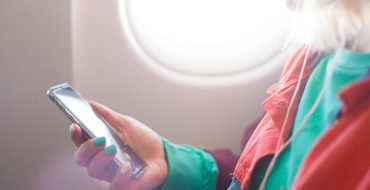 A girl listening to one of the best relationship podcasts on her phone while on a plane.