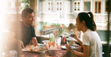 man and woman practicing good first date etiquette while eating pizza