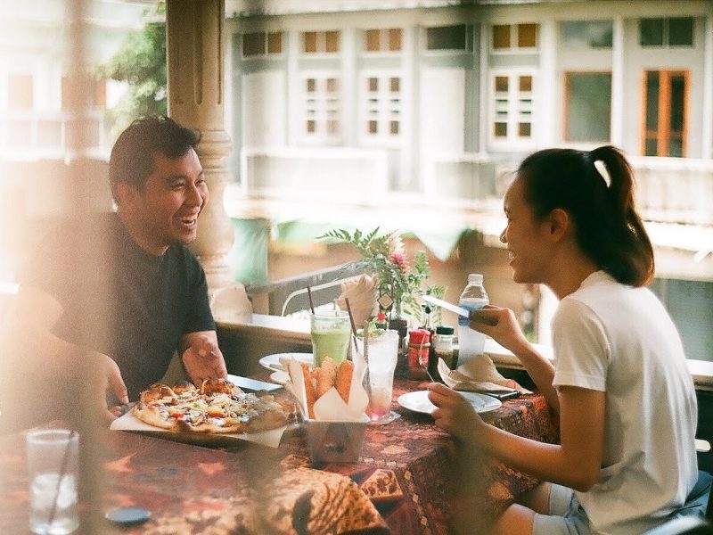 man and woman practicing good first date etiquette while eating pizza