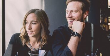 Couple dating at 40, enjoying cocktail and looking out the window together
