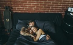 Happy couple lying in each other's arms in bed, enjoying a healthy sex life