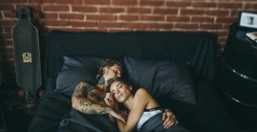 Happy couple lying in each other's arms in bed, enjoying a healthy sex life