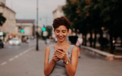 Attractive young woman smiling while using correct Tinder etiquette on her mobile phone